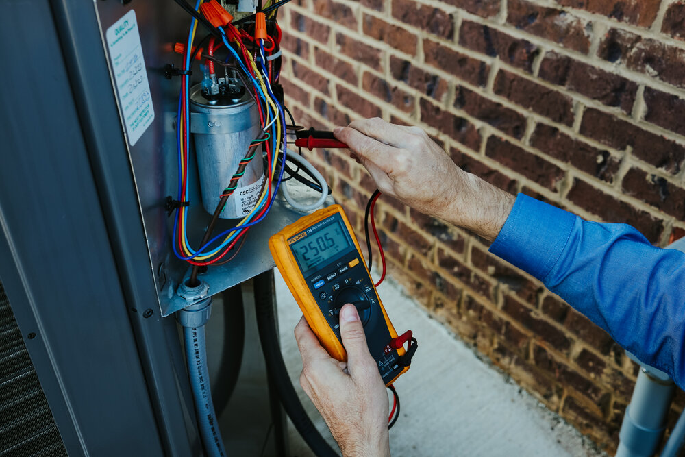 Our Comfort A/C technician testing the voltage of air conditioner components